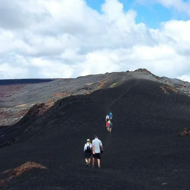 Turista caminando sobre campos de lava en el Volcán Sierra Negra
