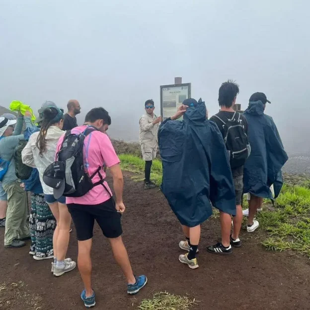 Group of hikers walking through the mist at the top of the volcano