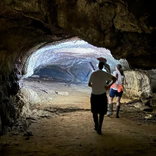 Persona ingresando a un túnel de lava iluminado naturalmente